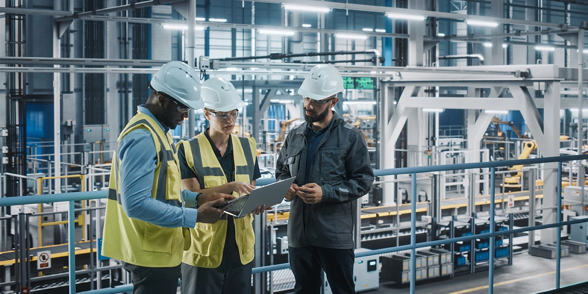 3 cyber security officers in a factory look at a tablet together